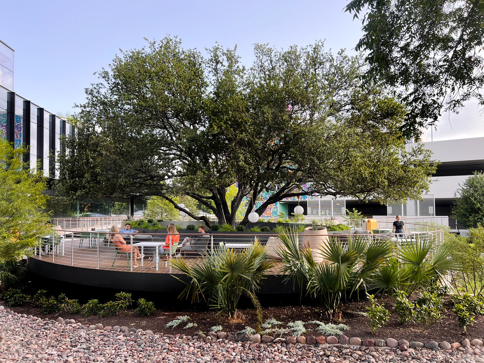 Victory Plaza — the oval deck seen across the palm and river-rock garden
