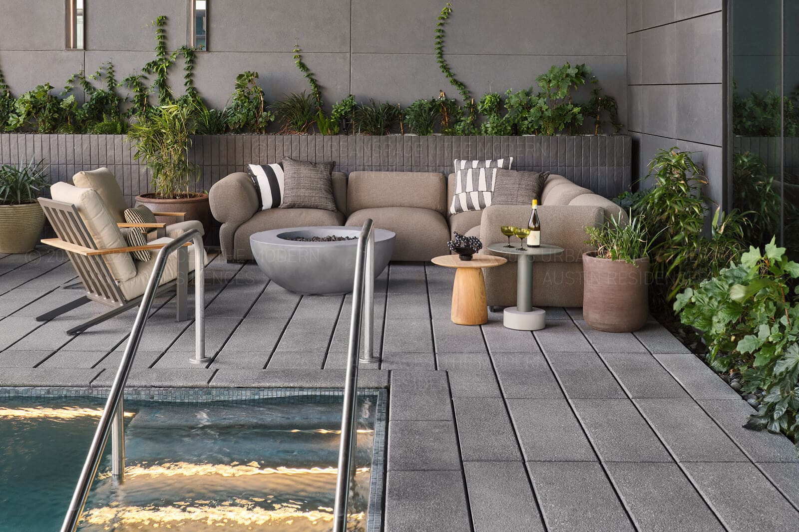 Spa pool and fire bowl on a terrace, ivy and ferns on the wall behind