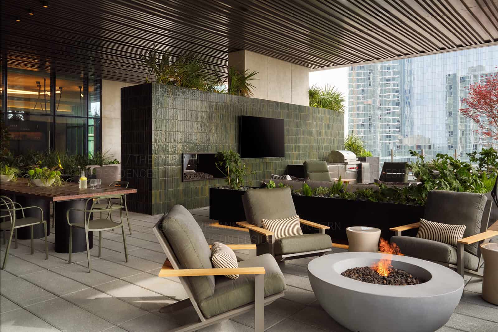 Fire pit lounge on a terrace, glazed green tile mass and planted troughs behind