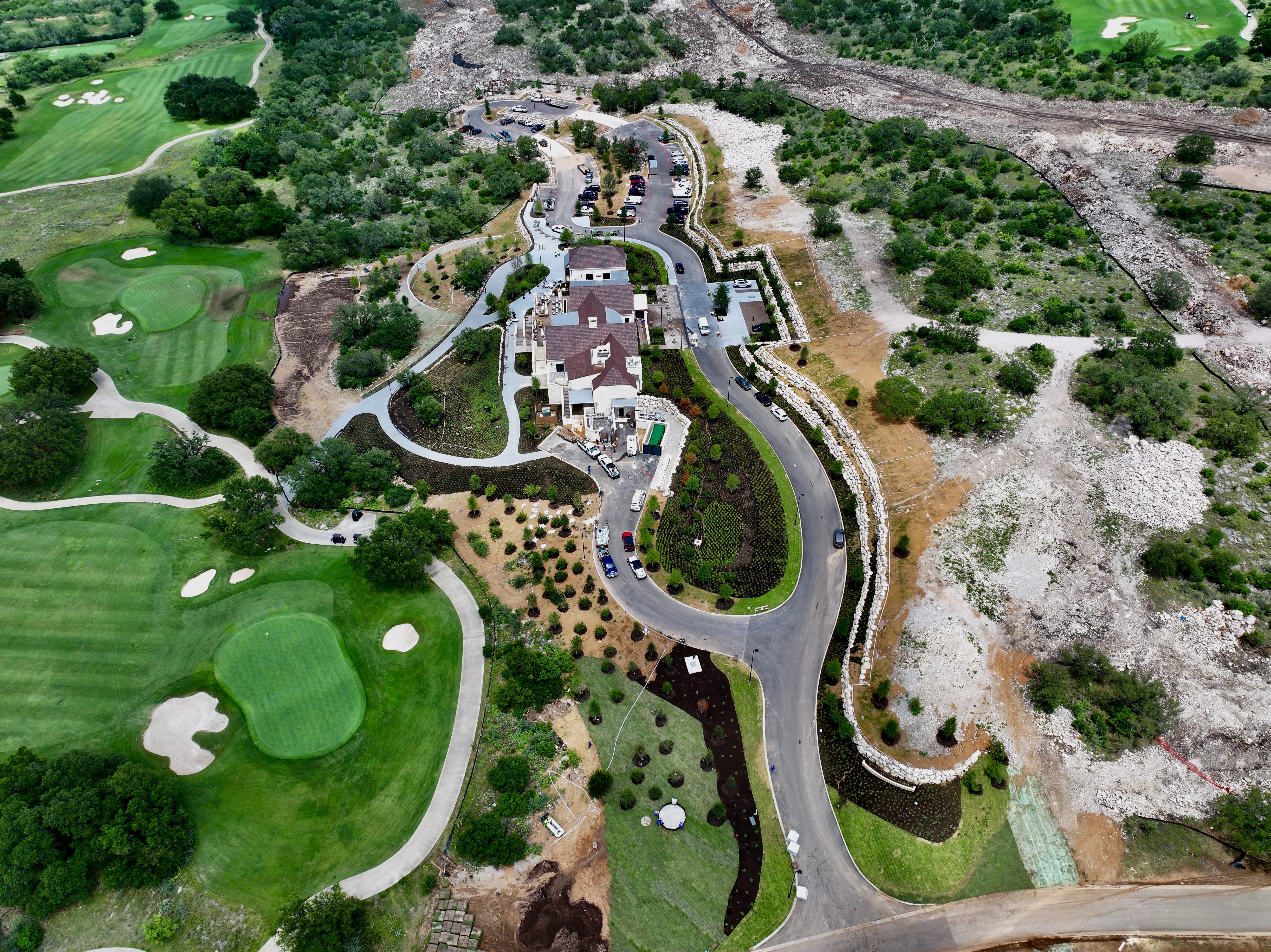 High aerial of the clubhouse complex between the golf greens and the cleared limestone